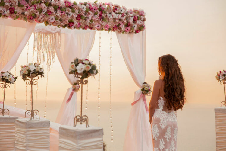 wedding ceremony. brunette bride standing by wreath arch with fl